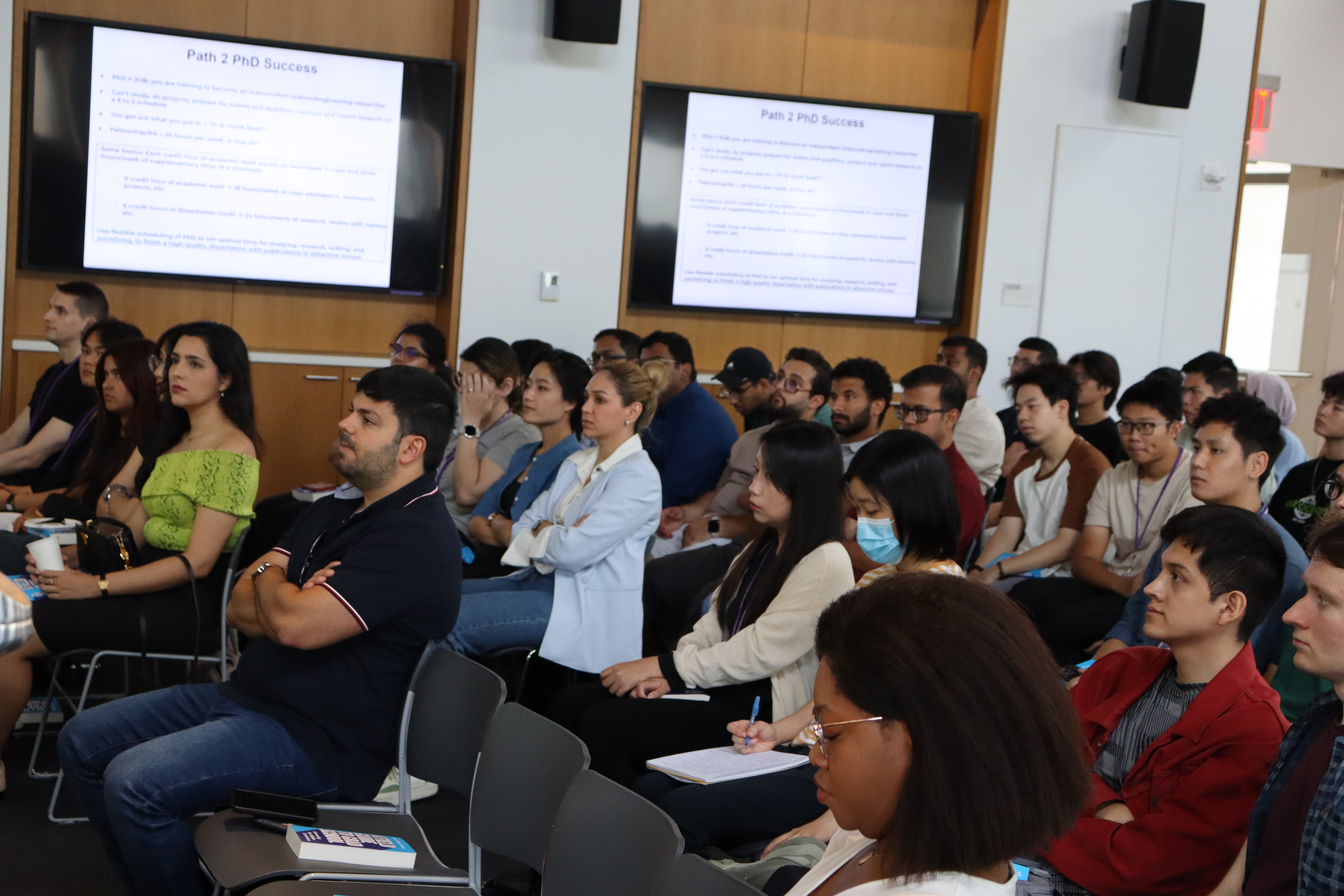 PhD students from Fall 2024 watching the presentation at orientation